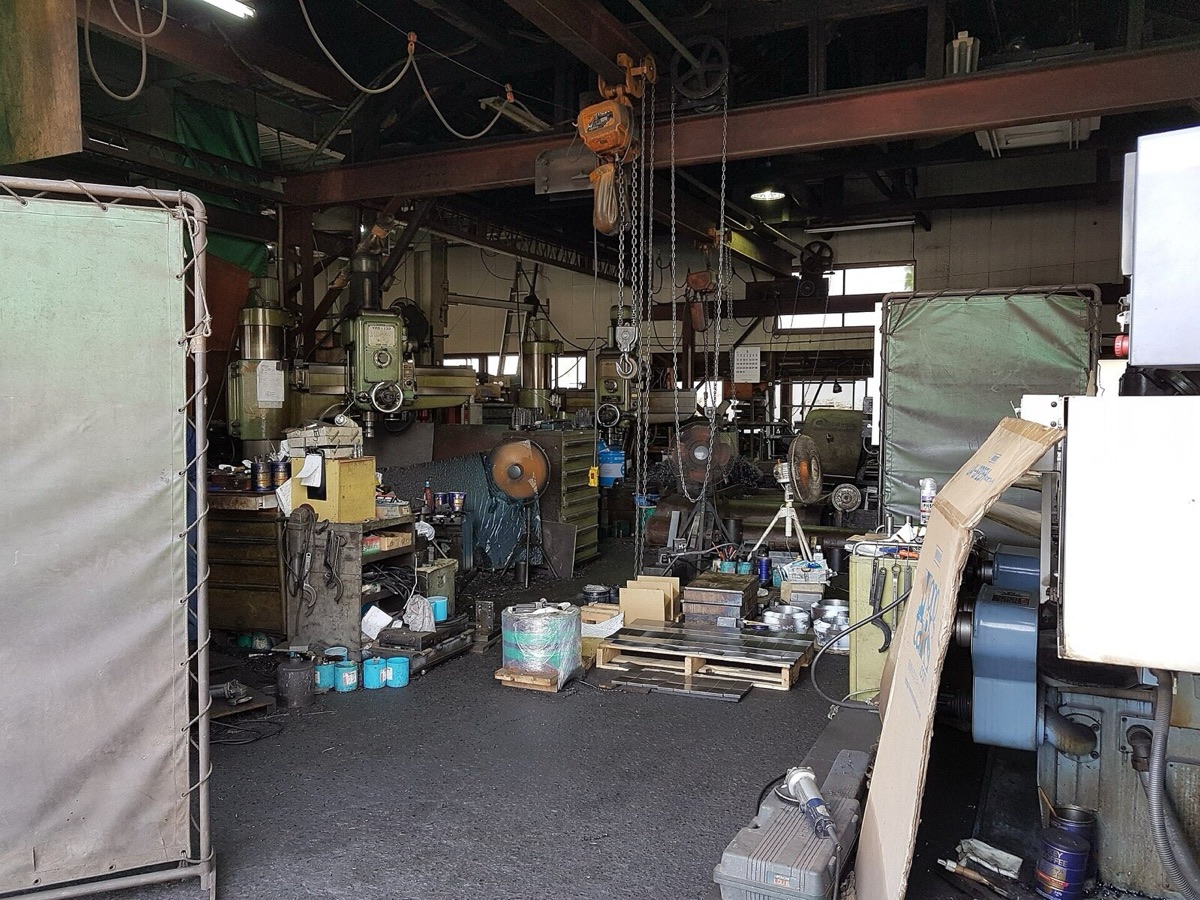 町工場の作業場。ボール盤や工具、資材が並ぶ