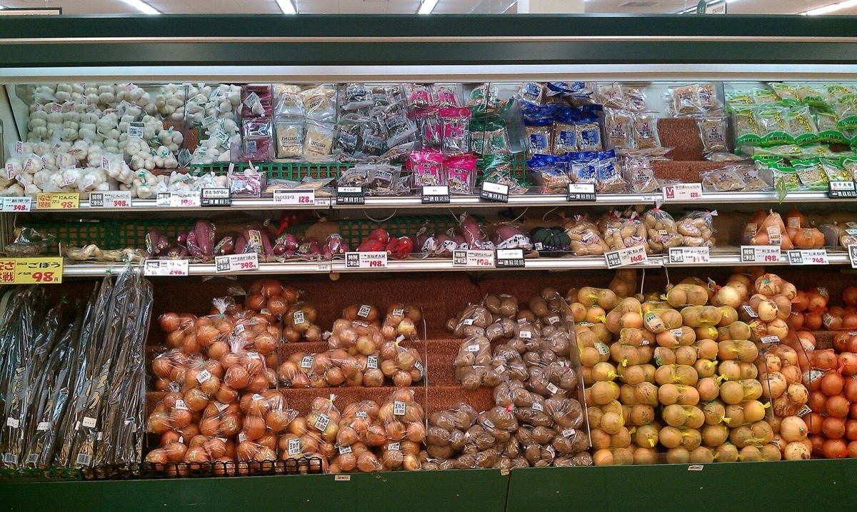 スーパーの野菜売り場。玉ねぎやじゃがいもなどが値札つきで並ぶ